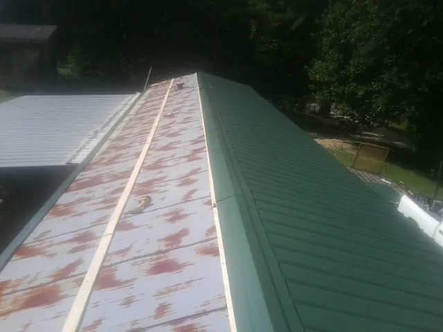 Old rusted panels beside newly installed green metal roofing — Wind Damage Roof Repair by Roofing Brothers in Pinesdale