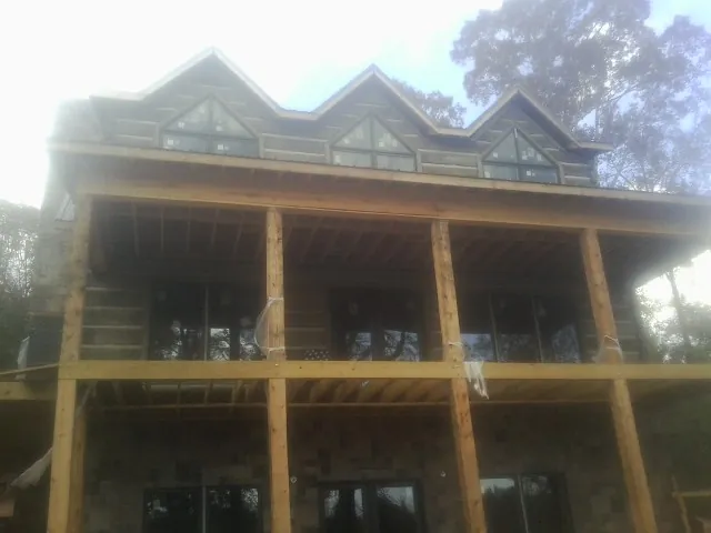 Dormers and porch framing on a large log home under construction — Roof Coating work by our crew in Pinesdale
