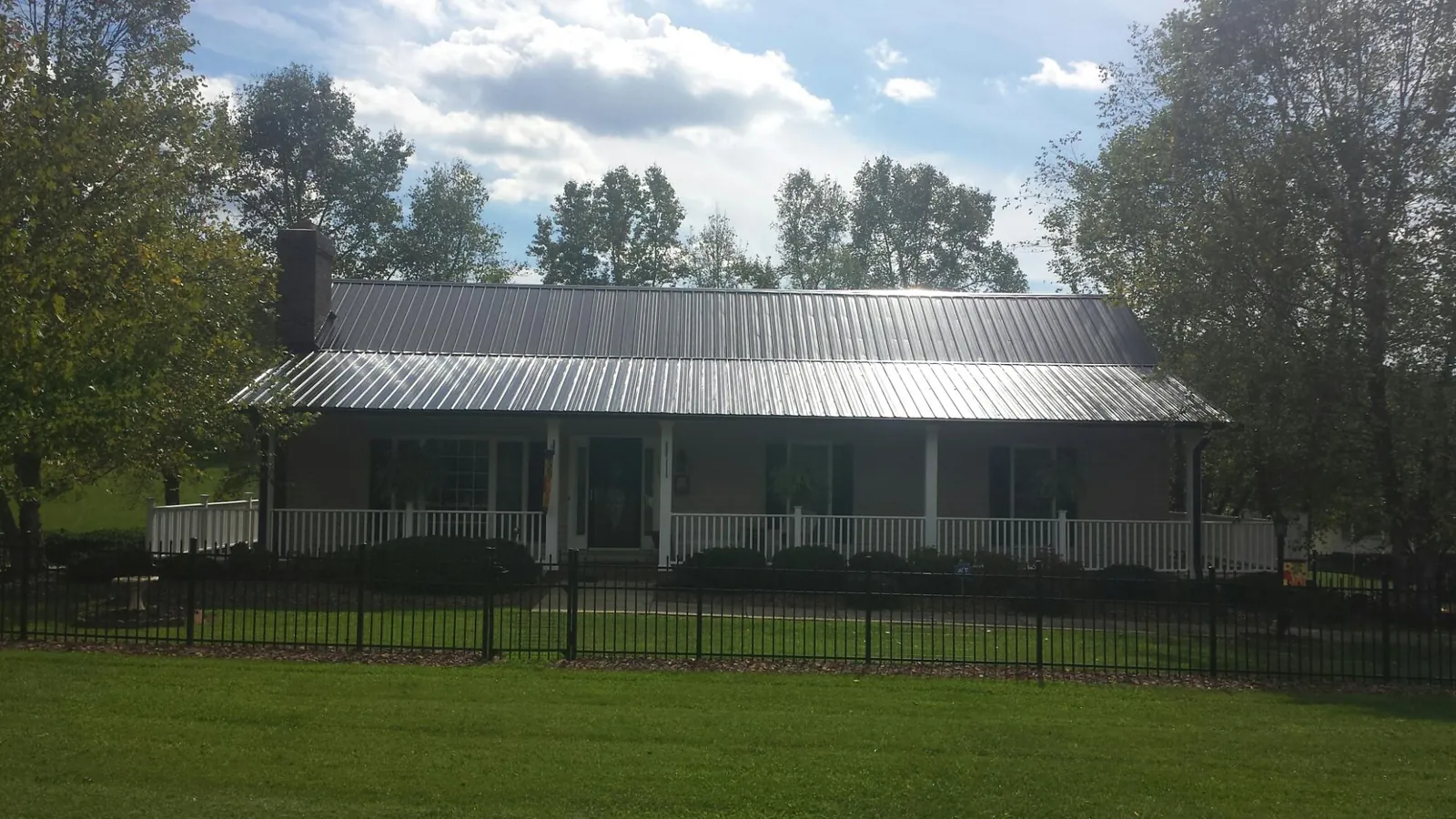 Gray metal roof on a brick ranch with a full width front porch — Gutter Guard Installation work by our crew in Pinesdale