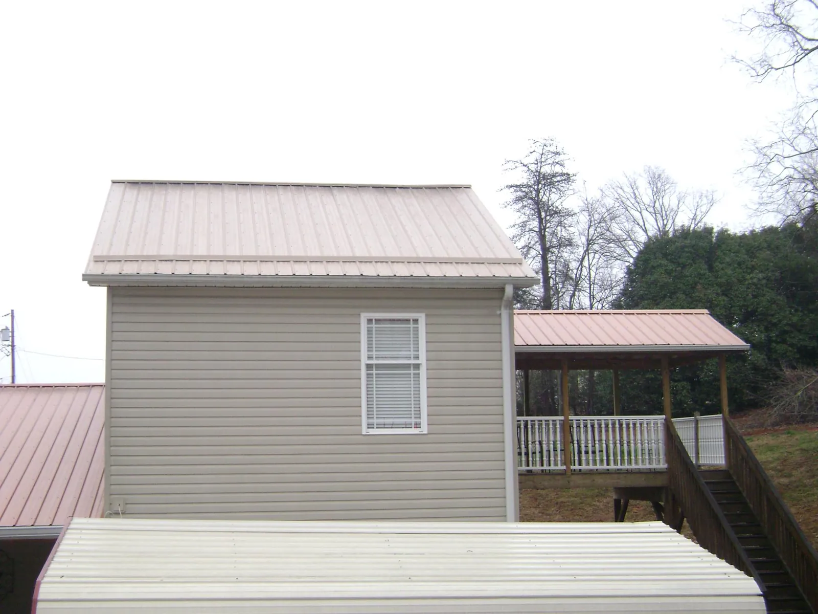 Tan metal roofs on a two story addition and attached porch, from a Roof Replacement job in Pinesdale