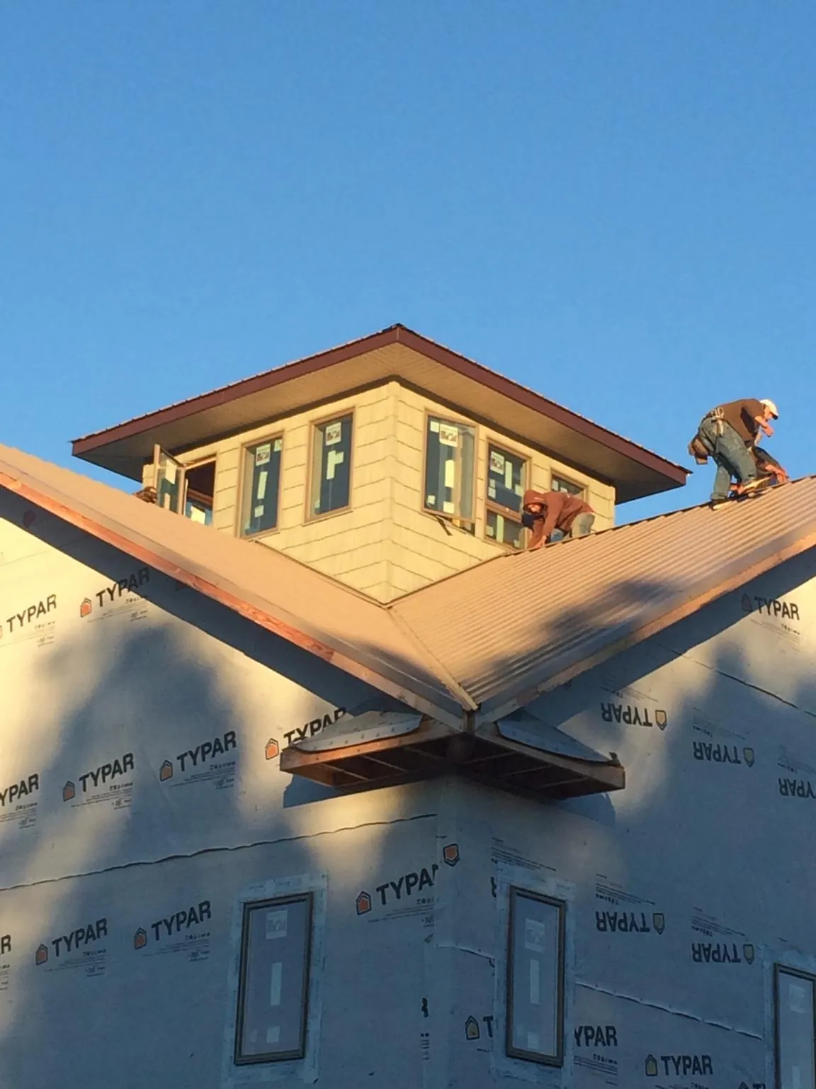 Roofers working around a rooftop cupola on a new metal roof at sunset — Roof Waterproofing in Pinesdale by Roofing Brothers